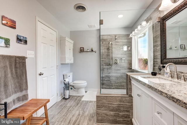 bathroom with a shower with shower door, toilet, and vanity