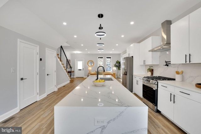 kitchen with appliances with stainless steel finishes, white cabinetry, sink, and wall chimney exhaust hood