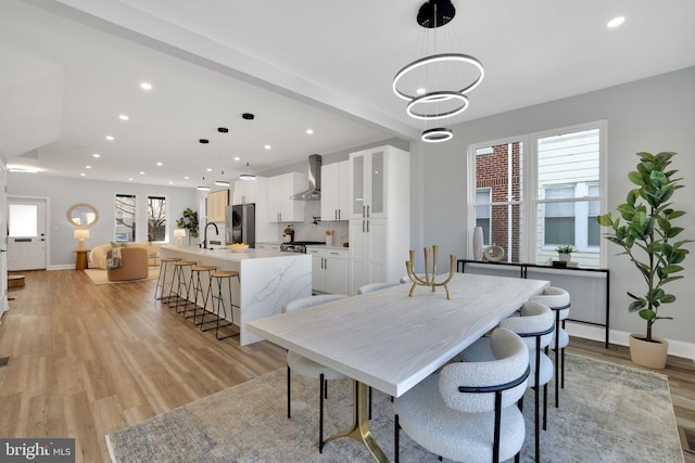 dining area with an inviting chandelier, light hardwood / wood-style flooring, and sink