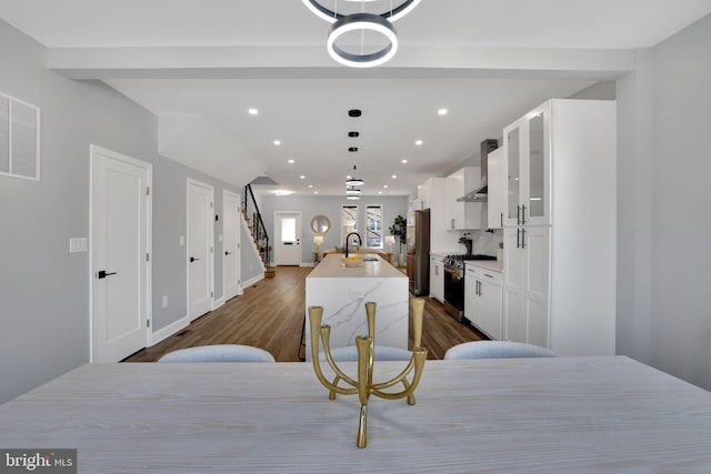 kitchen with white cabinets, appliances with stainless steel finishes, wall chimney range hood, and sink