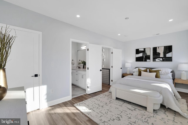 bedroom with light hardwood / wood-style floors and ensuite bathroom