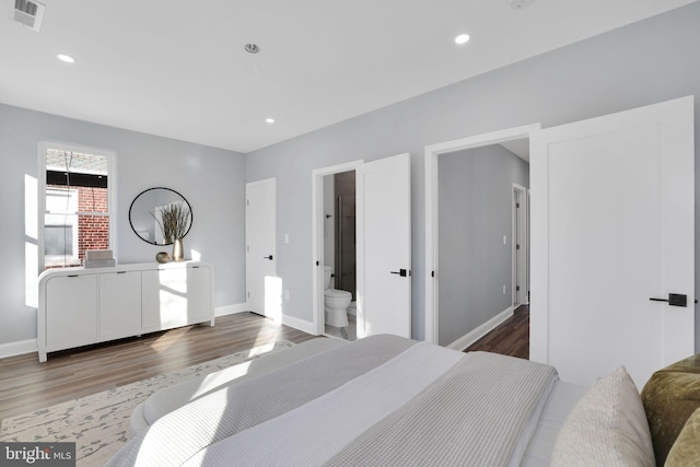 bedroom with hardwood / wood-style floors and connected bathroom