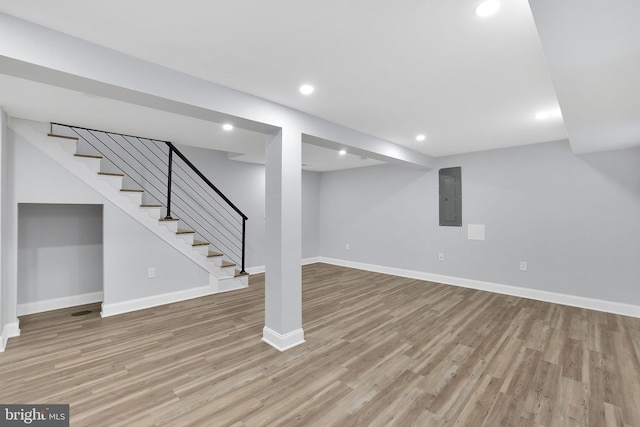 basement with electric panel and light hardwood / wood-style floors