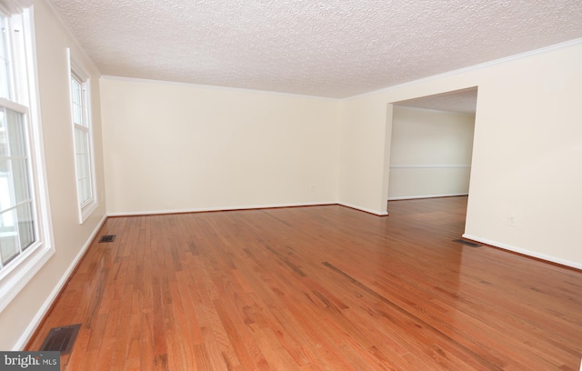 empty room featuring wood-type flooring, a healthy amount of sunlight, and a textured ceiling