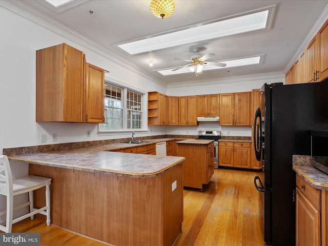 kitchen with ornamental molding, stainless steel stove, black fridge, and kitchen peninsula