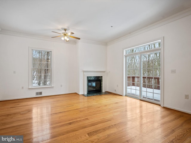 unfurnished living room featuring crown molding, a healthy amount of sunlight, and a fireplace