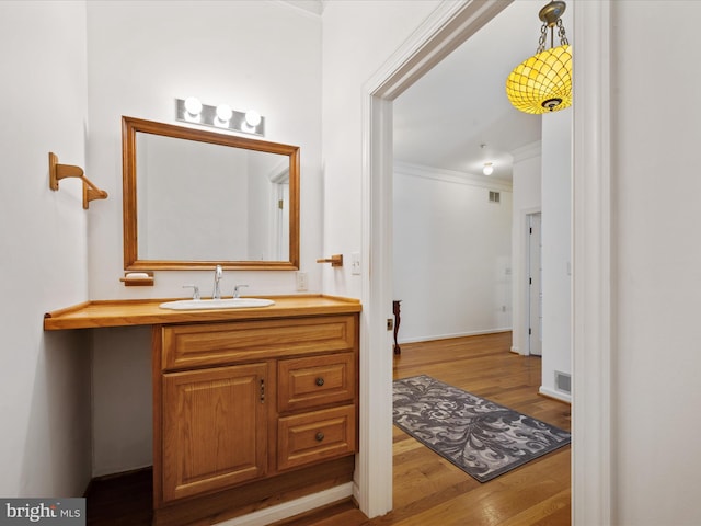 bathroom featuring vanity, wood-type flooring, and crown molding