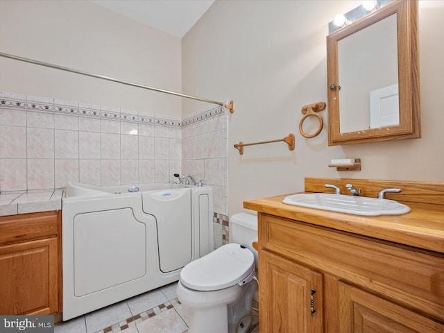 bathroom featuring toilet, vanity, tile patterned flooring, and a tub to relax in