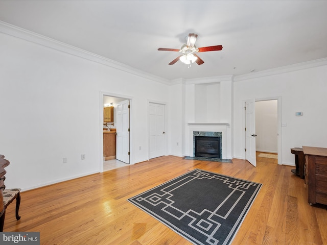 living room with ceiling fan, wood-type flooring, crown molding, and a fireplace