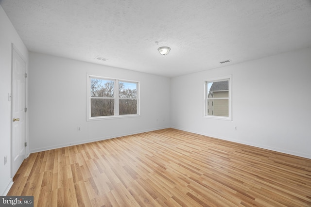 empty room with light hardwood / wood-style floors and a textured ceiling