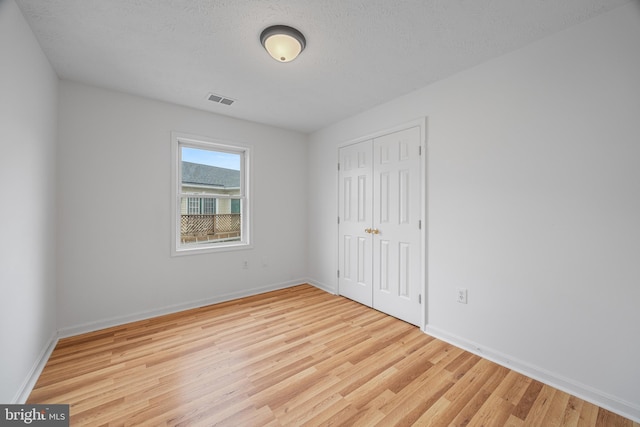 unfurnished bedroom featuring light hardwood / wood-style floors, a closet, and a textured ceiling