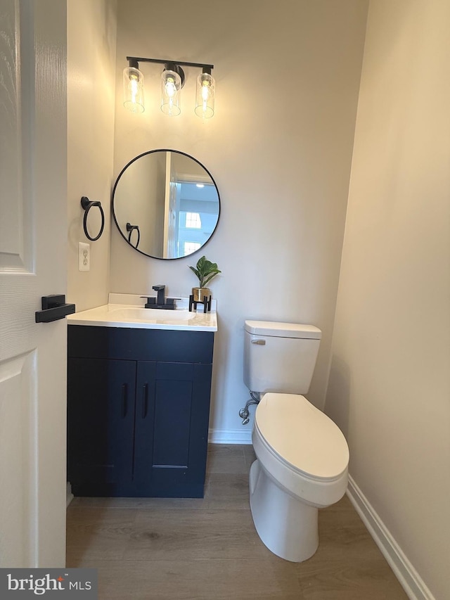 bathroom featuring toilet, hardwood / wood-style floors, and vanity