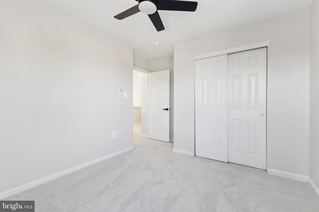 unfurnished bedroom featuring ceiling fan, light colored carpet, and a closet