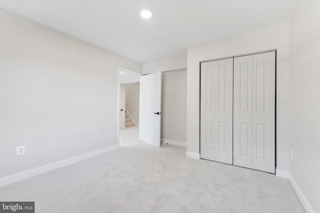 unfurnished bedroom with light carpet and a closet