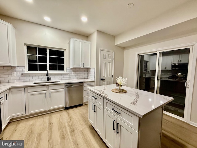 kitchen with white cabinets, dishwasher, a center island, sink, and backsplash