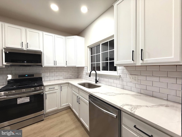 kitchen with white cabinets, light stone countertops, sink, and stainless steel appliances