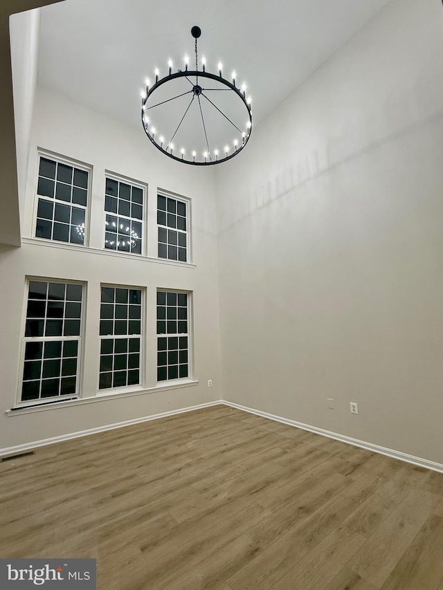 spare room with an inviting chandelier and hardwood / wood-style floors