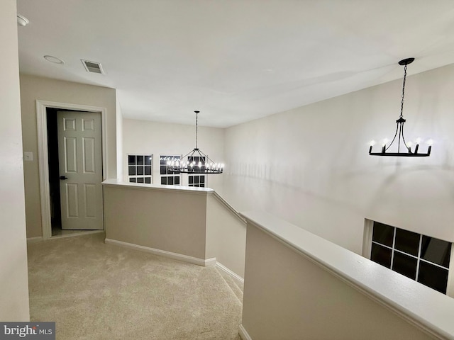 hall with light carpet and a notable chandelier