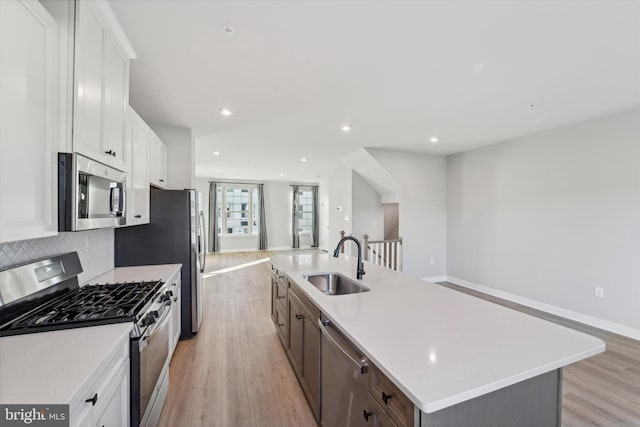 kitchen featuring white cabinets, stainless steel appliances, and an island with sink