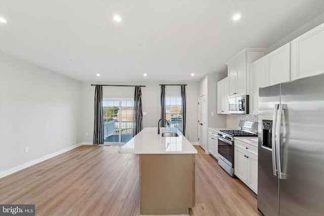 kitchen with stainless steel appliances, an island with sink, decorative backsplash, white cabinets, and sink