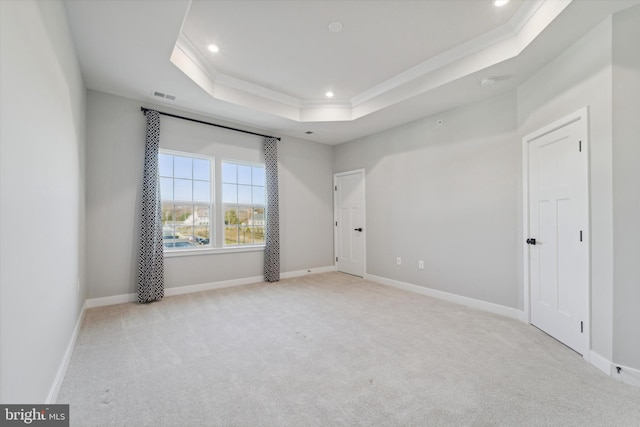 unfurnished room featuring a raised ceiling, crown molding, and light colored carpet