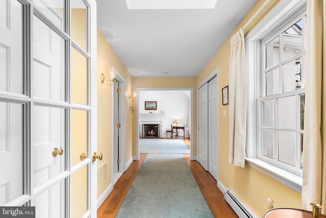 corridor with a baseboard radiator and wood-type flooring