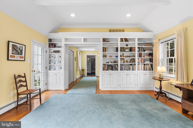 interior space featuring baseboard heating, vaulted ceiling, and wood-type flooring