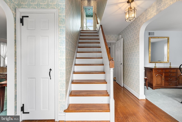 stairs featuring a notable chandelier and wood-type flooring