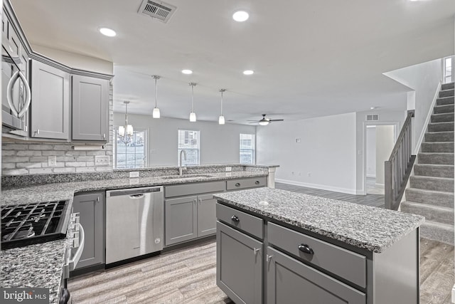 kitchen with sink, gray cabinetry, stainless steel appliances, and a kitchen island