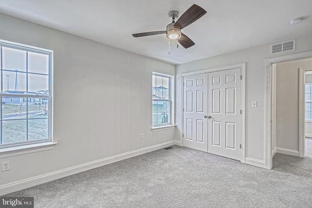 unfurnished bedroom with ceiling fan, light colored carpet, and a closet