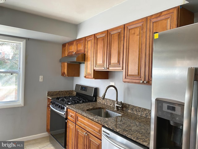 kitchen with sink, appliances with stainless steel finishes, and dark stone countertops