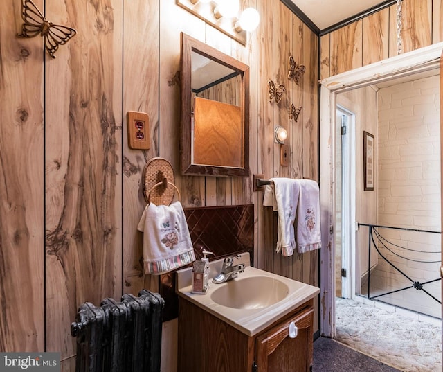 bathroom with radiator heating unit, vanity, and wood walls