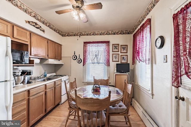 kitchen featuring white appliances, light wood-type flooring, ceiling fan, a baseboard heating unit, and sink