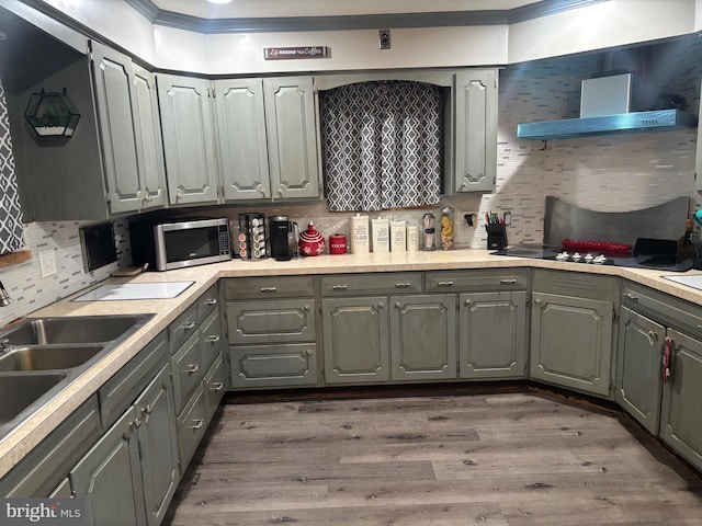 kitchen featuring wall chimney range hood, backsplash, dark hardwood / wood-style flooring, gray cabinetry, and sink