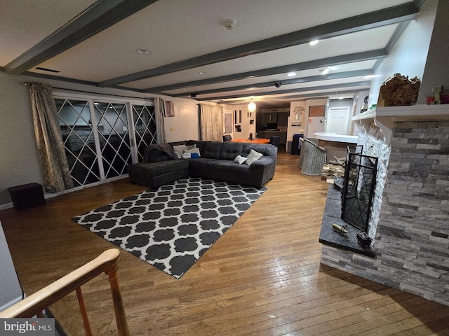 living room featuring a fireplace, wood-type flooring, and beamed ceiling