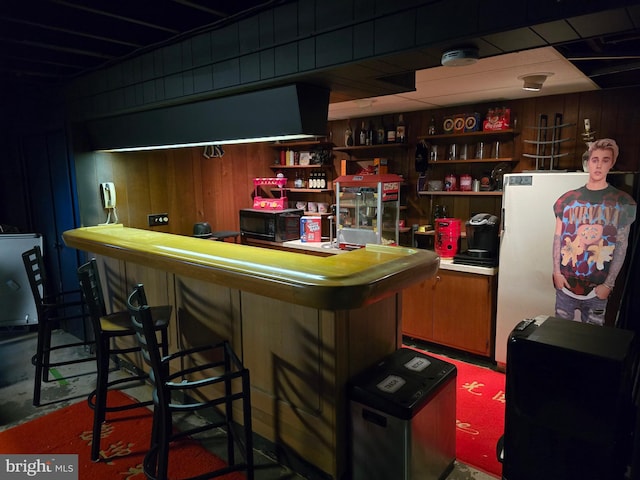 bar featuring white fridge and wooden walls