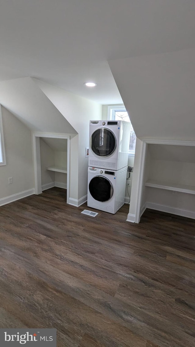 washroom with dark wood-type flooring and stacked washer and clothes dryer