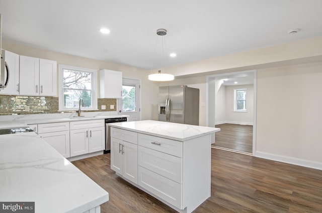 kitchen with pendant lighting, sink, white cabinets, a center island, and stainless steel appliances