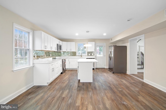 kitchen featuring appliances with stainless steel finishes, a kitchen island, pendant lighting, decorative backsplash, and white cabinets