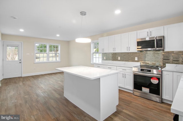 kitchen featuring appliances with stainless steel finishes, a center island, tasteful backsplash, white cabinets, and decorative light fixtures