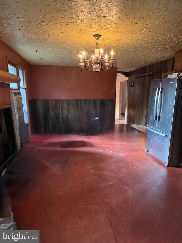 unfurnished living room featuring a textured ceiling, concrete floors, and a chandelier