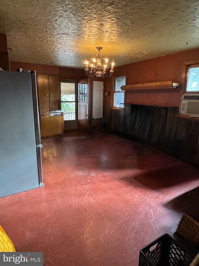 unfurnished dining area featuring a chandelier, dark floors, cooling unit, and a textured ceiling