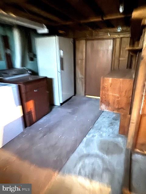 unfinished basement featuring freestanding refrigerator