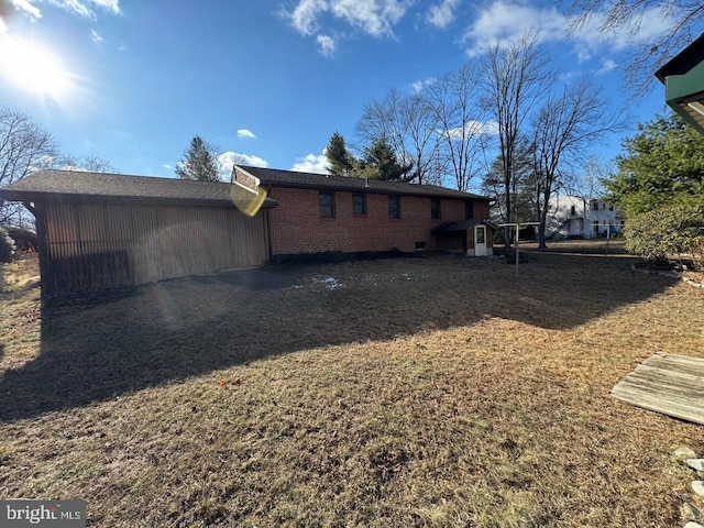 back of house featuring brick siding and a yard