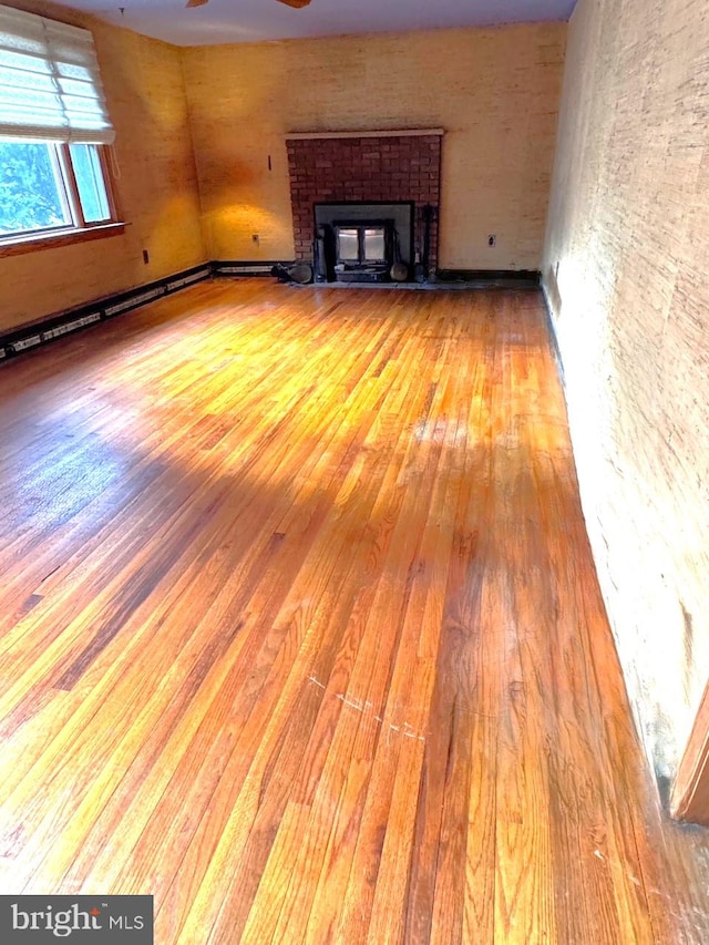 unfurnished living room with a ceiling fan, a brick fireplace, and light wood-style floors