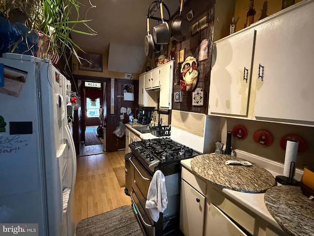 kitchen with sink, gas stove, light hardwood / wood-style flooring, white fridge with ice dispenser, and white cabinets