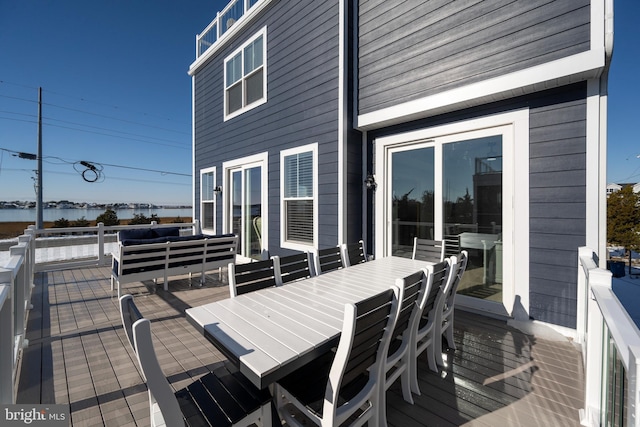 deck with an outdoor living space and a water view