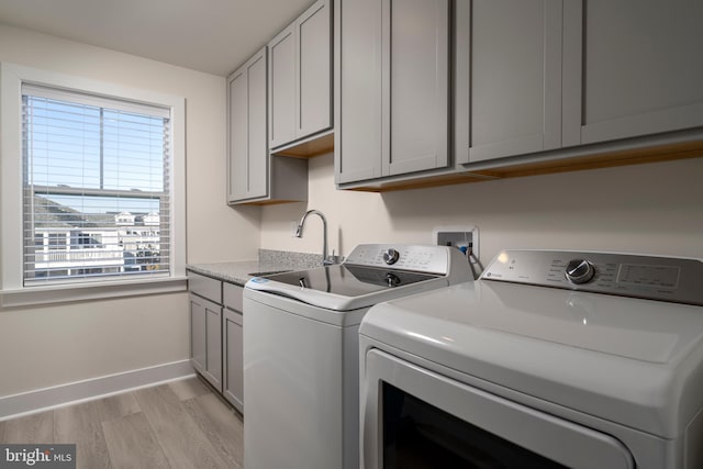 laundry area with independent washer and dryer, cabinets, light hardwood / wood-style flooring, and a healthy amount of sunlight