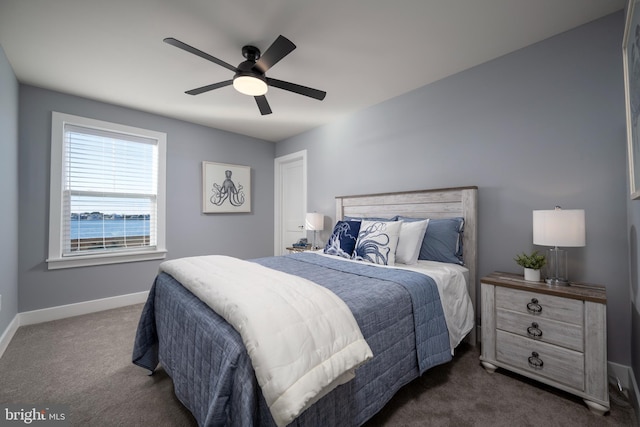 bedroom with ceiling fan, a water view, and dark colored carpet