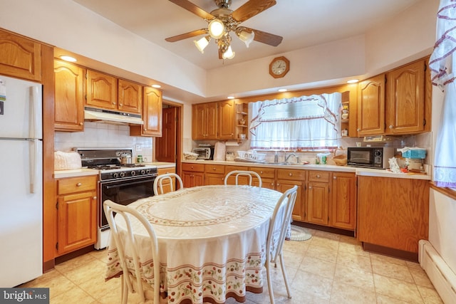 kitchen featuring sink, white fridge, ceiling fan, backsplash, and gas range